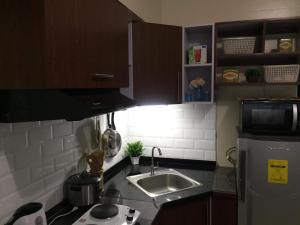 a small kitchen with a sink and a microwave at Joaquim Vacation Homes in Davao City