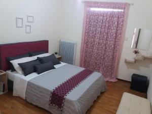 a bedroom with a large bed and a pink curtain at Comfortable 4th fl flat ideal for up to 8 people in Pyrgos