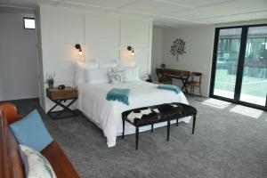 - une chambre avec un grand lit blanc et une table dans l'établissement 157 Field Way Luxury Lodge, à Waikanae