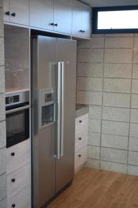 - un réfrigérateur en acier inoxydable dans une cuisine avec des placards blancs dans l'établissement 157 Field Way Luxury Lodge, à Waikanae