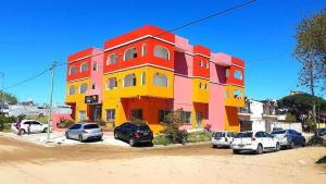 un edificio colorato con auto parcheggiate di fronte di Médanos Hotel a San Clemente del Tuyú
