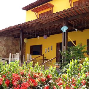 een geel huis met rode bloemen ervoor bij Sol Hostel & Pousada Maragogi in Maragogi