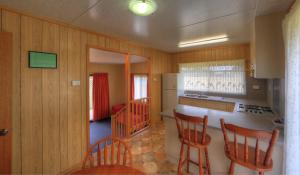 BIG4 Kelso Sands Holiday & Native Wildlife Park في Kelso: مطبخ بجدران خشبية وكراسي خشبية وكاونتر