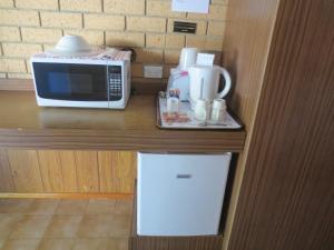 a microwave on top of a counter next to a cup of coffee at Aspley Pioneer Motel in Brisbane
