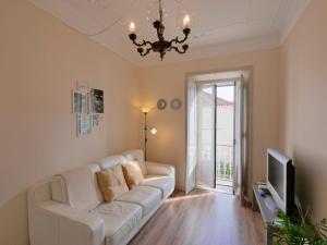 a living room with a white couch and a television at Casa da Parede - Beach & Mountain in Parede