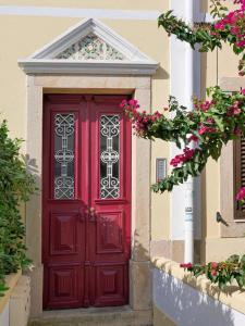 czerwone drzwi na budynku z różowymi kwiatami w obiekcie Casa da Parede - Beach & Mountain w mieście Parede