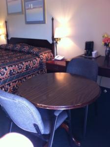 Habitación de hotel con mesa, sillas y cama en Gold Inn en Hutchins