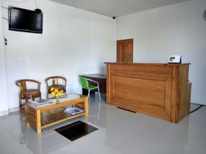 uma sala de estar com uma televisão e uma mesa e cadeiras em Victory Hotel em Ruteng