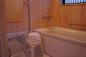 a bathroom with a tub and a stool next to a toilet at Sumiyoshiya in Kanazawa