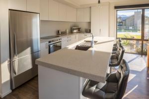 a kitchen with a refrigerator and a counter with chairs at Retreat for all seasons in Wanaka