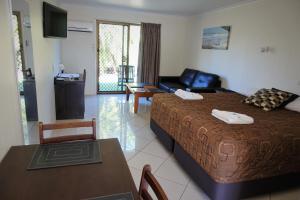 a bedroom with a bed and a table and a couch at Pacific Palms Motor Inn in Marcoola