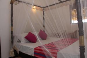 a bedroom with a canopy bed with red pillows at Laguna Surfing Stay in Midigama