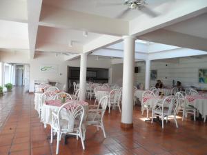 um quarto com cadeiras e mesas brancas e pessoas ao fundo em Hotel PomMarine em Bridgetown