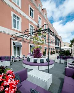 - une terrasse avec des meubles violets et blancs devant un bâtiment dans l'établissement SANA Silver Coast Hotel, à Caldas da Rainha