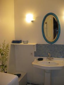 ein Bad mit einem Waschbecken und einem Wandspiegel in der Unterkunft Gite des pâtissons in La Foret Du Parc