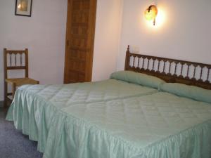 een slaapkamer met een groot bed en een stoel bij Hotel Puerta Romeros in Burgos