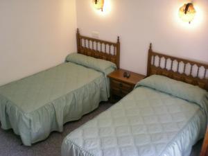 a room with two beds and a wooden table at Hotel Puerta Romeros in Burgos