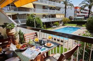 a balcony with a table with food and a pool at Beachfront Resort Apartment in Castelldefels