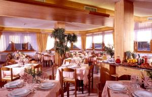 a dining room with tables and chairs and windows at Hotel & Appartamenti Al Larice in Ronzone