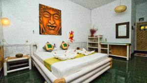 a bedroom with a large bed with a painting on the wall at Rumah Kundun in Gili Trawangan