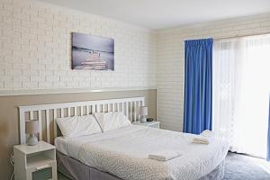 a bedroom with a large bed and a large window at Aquarius Merimbula in Merimbula