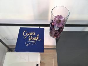 a glass vase with a flower next to a guest book at Albamare in Monterosso al Mare