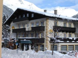 a large building with a snow covered mountain in the background at ALPINA Appartements Mallnitz in Mallnitz