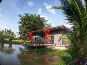 a house with red curtains next to a body of water at Sawan Srang Nang Kaew in Takhop +54 photos