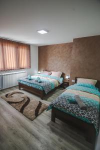 1 dormitorio con 2 camas y alfombra en Kristal Apartmani en Arandjelovac
