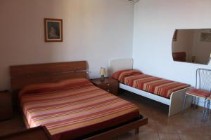 a bedroom with two beds and a chair and a mirror at La casetta in piazza in Porto Santo Stefano