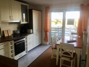 a kitchen with white cabinets and a table and a dining room at Heimathafen in Nordstrand