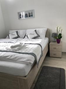 łóżko z białą pościelą i poduszkami w sypialni w obiekcie Panorama Apartments w Karlowych Warach