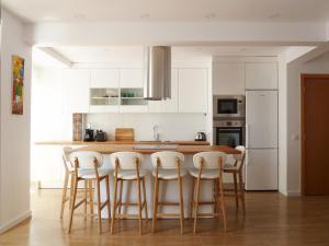 a kitchen with white cabinets and a table with stools at Ocean Breeze Apartment in Estoril