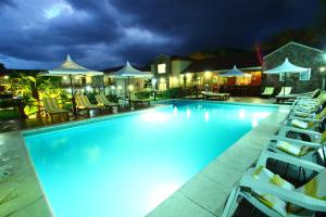a large swimming pool with chairs and umbrellas at night at Apart Hotel Las Palmeras in Villa General Belgrano