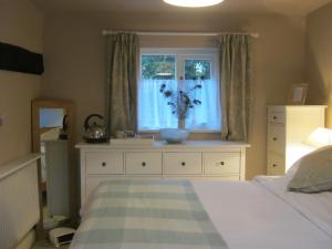 - une chambre avec un lit et une fenêtre avec un vase dans l'établissement THE MOATS - CODDINGTON A small private thatched cottage B&B located in quiet countryside between Ledbury and Malvern - convenient for the Malvern Three Counties Showground and 5 miles from excellent shops restaurants and Ledbury Poetry Festival, à Ledbury 7 autres photos