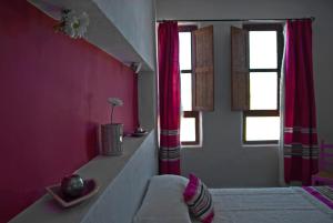 una sala de estar con paredes y ventanas de color rosa. en Olivares Rural en Los Albaricoques