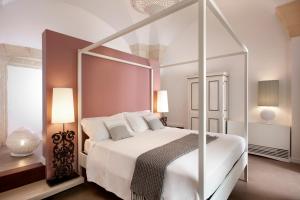 a white bedroom with a canopy bed with white pillows at Mantatelurè in Lecce