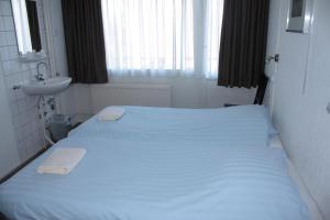 a bedroom with a white bed and a sink at Hotel 't Meertje in Vinkeveen