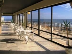 een balkon met tafels en stoelen en uitzicht op de oceaan bij Beach apartment... T1 with swimming pool (summer) in Costa da Caparica
