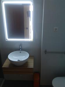 ein Badezimmer mit einem weißen Waschbecken und einem Spiegel in der Unterkunft Beach apartment... T1 with swimming pool (summer) in Costa da Caparica