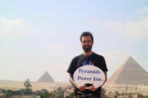 un hombre sosteniendo un cartel delante de las pirámides en Pyramids Power Inn, en El Cairo