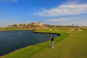 a man standing on a golf course next to a body of water at Bay La Sun Hotel and Marina - Emaar King Abdullah Economic City in King Abdullah Economic City