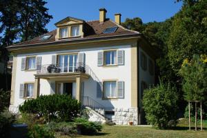 uma grande casa branca com uma varanda em Maujobia 31 em Neuchâtel