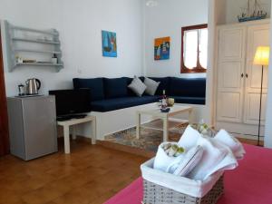 a living room with a blue couch and a tv at Anofli Suites in Skopelos Town