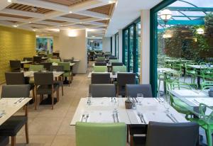 a restaurant with white tables and chairs and windows at Metropolitan Hotel in Tel Aviv