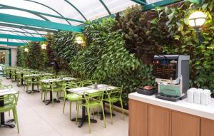 restauracja ze stołami i krzesłami oraz zieloną ścianą w obiekcie Metropolitan Hotel w Tel Awiwie