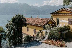 a house next to the water with mountains in the background at CHARMING MOMENT di Villa Porta - Casa Amatissima in Brezzo