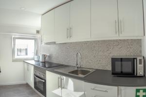 a kitchen with white cabinets and a sink and a microwave at Azuleixo in Aveiro