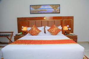 a bedroom with a large white bed with orange pillows at Tiffany Diamond Hotel Makunganya Street in Dar es Salaam