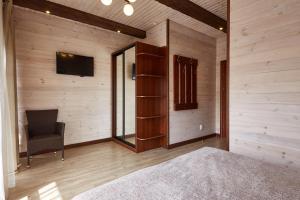 Habitación con paredes de madera, silla y TV. en Zlata, en Bukovel